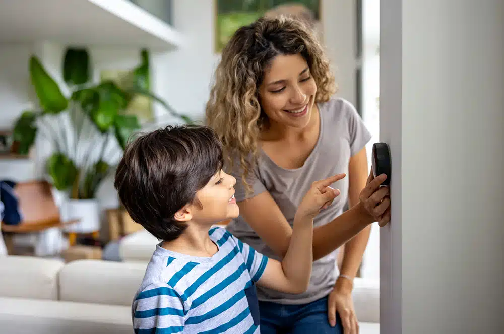A mother and son adjusting a thermostat
